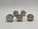 quatre petites horloges posées les unes sur les autres sur une surface blanche