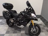 une moto noire garée dans une pièce au sol en damier