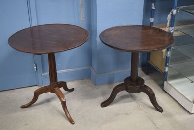 une paire de tables d'appoint anciennes sur pied, placées devant une vitrine en verre