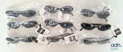 Plusieurs paires de lunettes de soleil sont emballées dans des sachets en plastique, posées sur une surface blanche