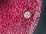 the inside of a red purse with a metal button on it