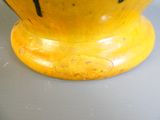 un vase jaune rayé de noir posé sur une table