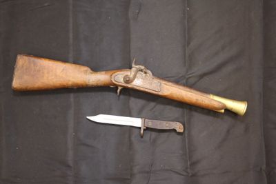un fusil et un couteau posés sur un tissu noir