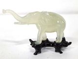 une statue d'éléphant posée sur un socle noir, sur fond blanc