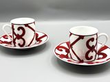 une paire de tasses à café rouges et blanches avec leurs soucoupes, posées sur une table