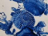 a blue and white plate with a vase of flowers on it