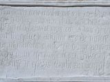 une vieille plaque en pierre portant une inscription, devant un mur de briques