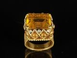 an image of a gold ring with a yellow stone surrounded by diamonds