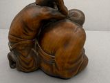 une petite statue représentant un homme assis sur un oreiller