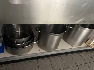 des casseroles et des poêles sont alignées sur une étagère dans une cuisine