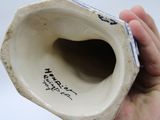 a hand holding a white vase with a black writing on it
