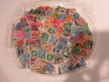 un récipient en plastique rempli de timbres-poste posé sur une table