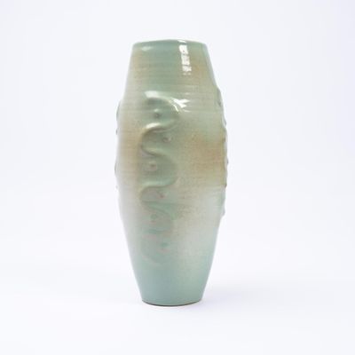 un vase vert posé sur une surface blanche