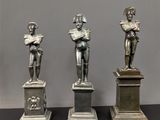 trois statues représentant un homme tenant un livre et une femme en train de lire un livre