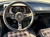 a steering wheel and dashboard of a car with a plaid seat cover