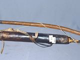 un long bâton en bois et une bouteille noire posés sur une surface bleue