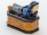 une figurine représentant un homme allongé sur une caisse