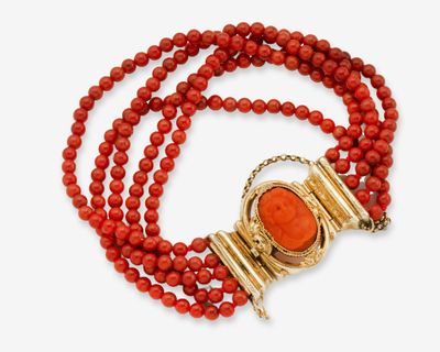 un collier de perles rouges muni d'un fermoir en or et d'un pendentif en pierre rouge