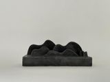 sculpture noire représentant une paire de chaussures posée sur une surface blanche