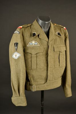 une veste d'uniforme militaire ornée d'écussons, posée sur un mannequin