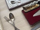 a box with silverware on a table with a knife, fork, spoon, and knife rest