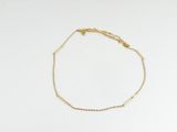 un bracelet en chaîne dorée orné d'une petite perle sur fond blanc