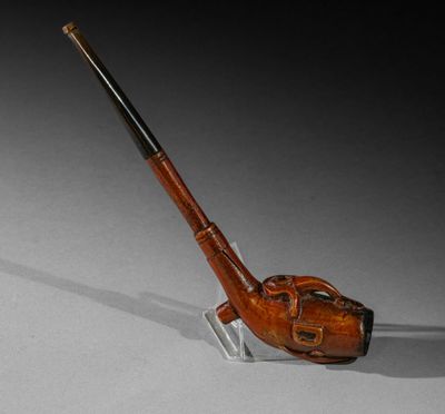 une vieille pipe posée sur un socle en verre, à côté d'un fond noir et blanc