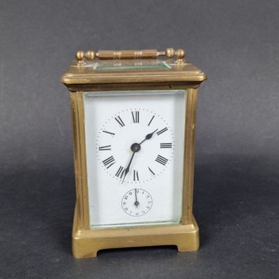 une petite horloge en or dont le cadran est orné de chiffres romains