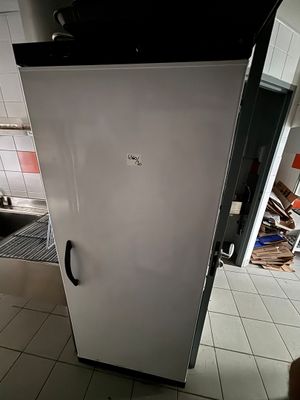 un réfrigérateur blanc dans une cuisine au sol carrelé