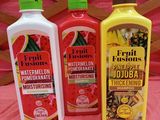 trois bouteilles d'eau aromatisée aux fruits (pastèque, citron et grenade) posées sur une nappe rose