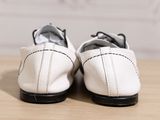 pair of white shoes on a wooden table with a white wall in the background