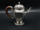 a silver teapot with a wooden handle on a black background