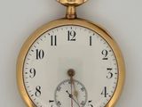 a close up of a gold pocket watch on a white surface