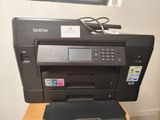 a black printer sitting on top of a wooden desk next to a computer