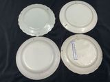 four white plates are sitting on a black surface