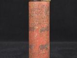 an old red and gold tin canister with a black background