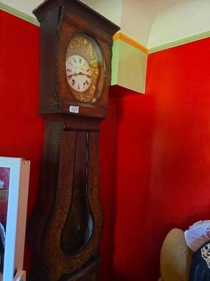 a grandfather clock in the corner of a room with a red wall