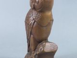 statue of an owl perched on a tree stump on a blue background