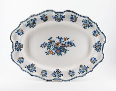 des fleurs bleues et orange disposées sur un plateau blanc, sur fond blanc