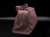 pink leather handbag on a black surface with a black background