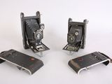 three old cameras sitting next to each other on a white surface