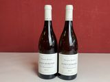deux bouteilles de vin posées sur une table devant un mur rouge