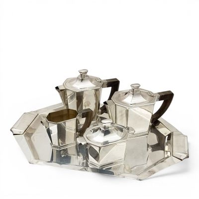 a silver tea set on a tray on a white surface
