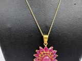 a gold necklace with a pink flower pendant on a mannequin