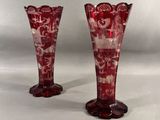 une paire de vases en verre rouge posés sur une table blanche