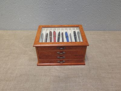 a small wooden box with pens in it on a table