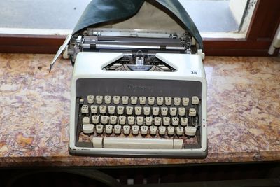 une vieille machine à écrire posée sur une table près d'une fenêtre