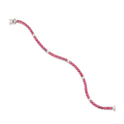un gros plan d'un bracelet orné de pierres roses sur fond blanc