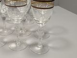 twelve wine glasses with gold rims on a white table