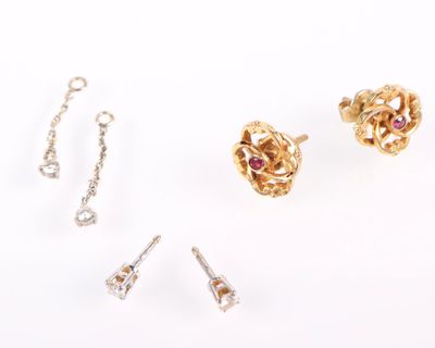 trois paires de boucles d'oreilles et une chaîne posées sur une surface blanche